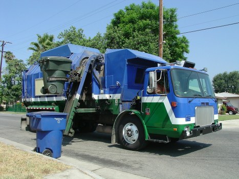 Workers securing waste into skip wearing high-visibility and PPE