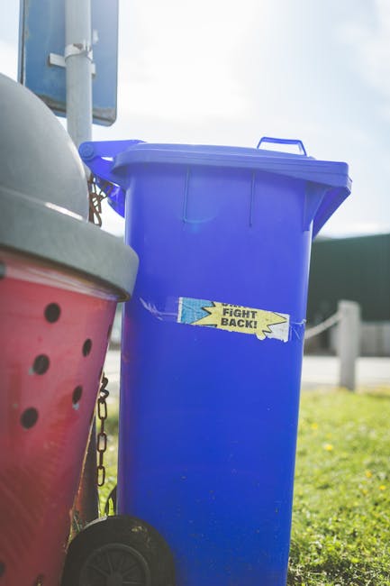 A large pile of mixed household rubbish and waste materials is spread across a flat surface, likely a driveway or outdoor area. The debris includes crumpled paper, used plastic bottles, aluminum cans,